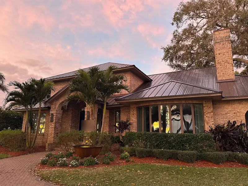 Brick family home with a new bronze standing-seam metal roof at sunset