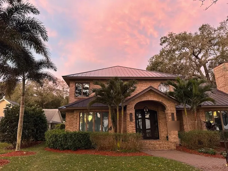 Front entrance of a brick home under a new bronze metal roof