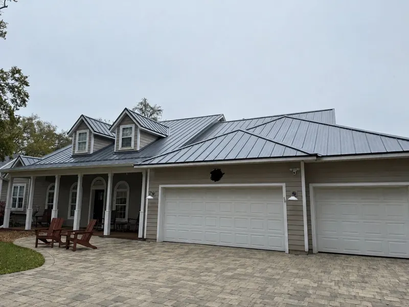 Grey craftsman-style home with a new silver standing-seam metal roof