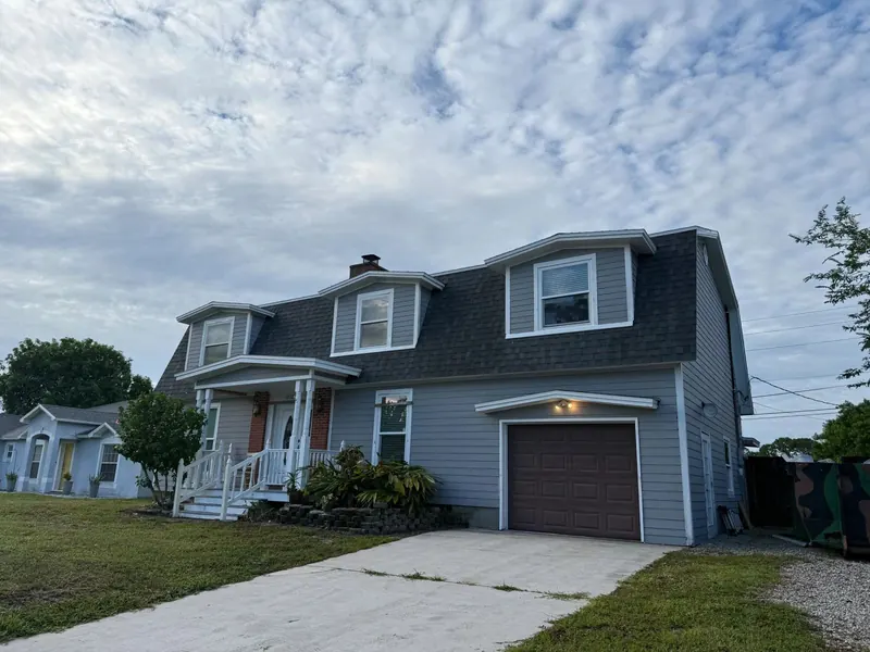 Blue two-storey home with a new dark shingle roof seen from the street
