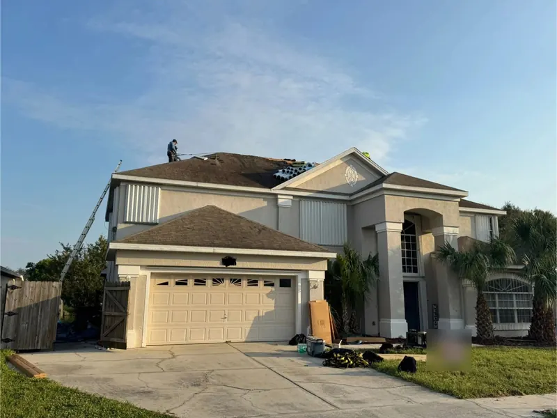 Crew finishing a shingle re-roof on a two-storey stucco home