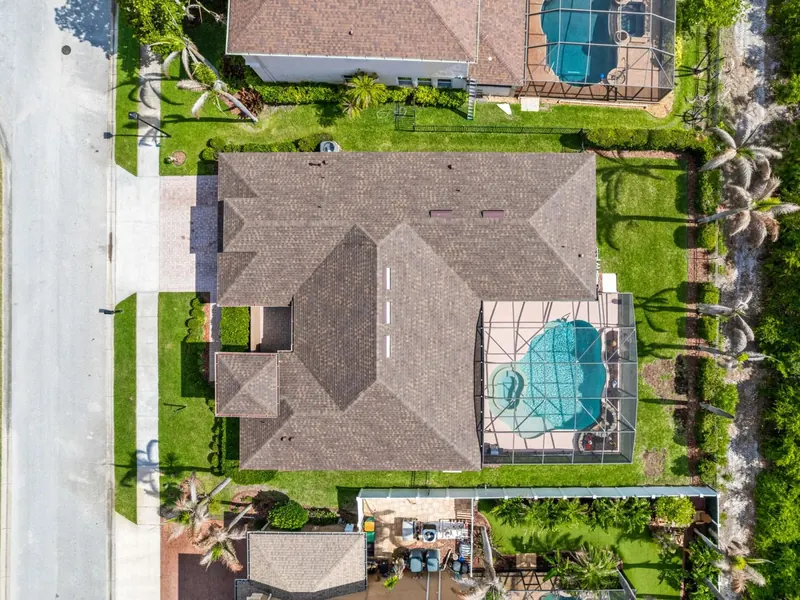 Aerial view of a home with a new brown shingle roof beside a screened pool