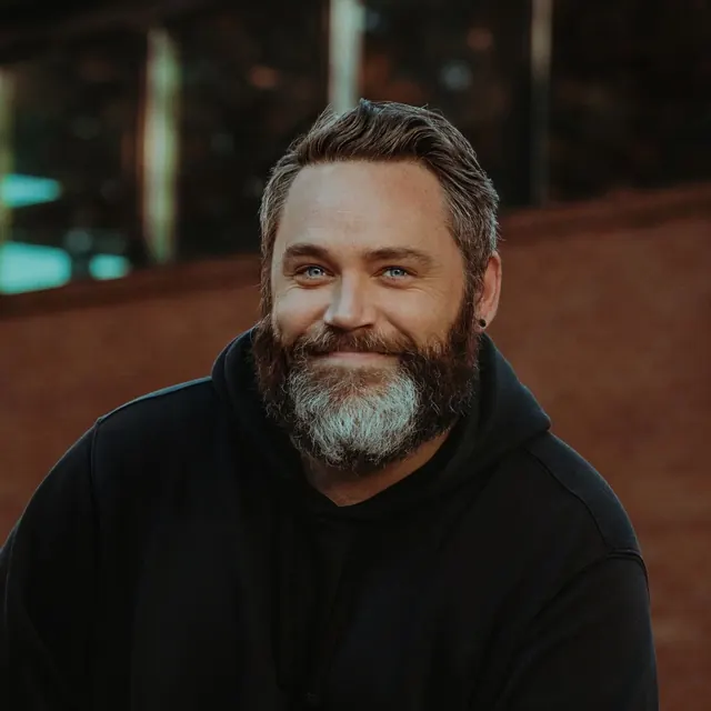 Portrait of a smiling bearded man in a black hoodie