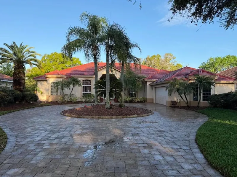 Single-storey home with a terracotta tile roof behind a circular paver driveway