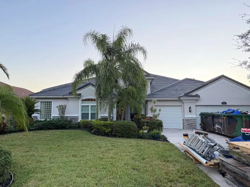 White home with a grey concrete tile roof and a neat front lawn